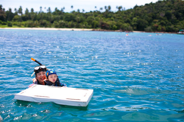 Happy snorkel mother and son having fun in ocean water snorkeling on Caribbean vacation in Thailand