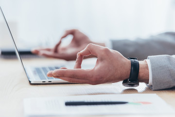 close-up partial view of businessman meditating while working with laptop in office