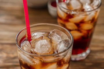 Glass of tasty cold cola drink on table, closeup