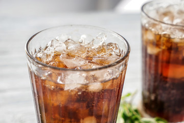 Glass of tasty cold cola drink on table, closeup