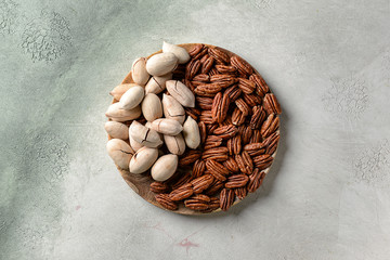 Plate with pecan nuts on light background