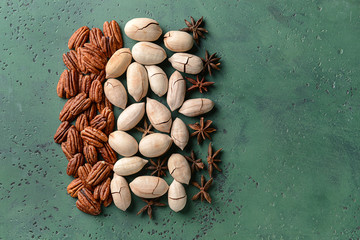 Tasty pecan nuts with anise on color background