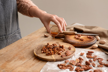 Woman preparing candied pecan nuts at table