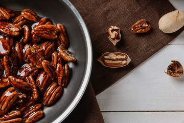 Frying pan with candied pecan nuts on white table