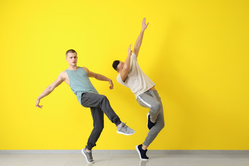 Fototapeta na wymiar Young men dancing near color wall