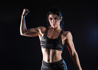 Obraz na płótnie Canvas Sporty muscular woman on dark background
