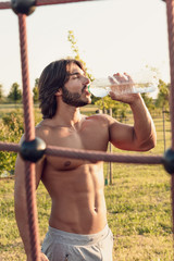 Shirtless man with six-pack abdomen drinking water
