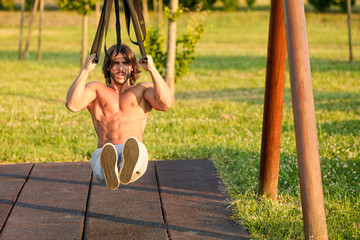 Young man with six-pack exercising in the park