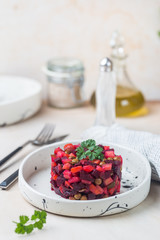 Russian beetroot salad vinaigrette in a white plate over light background