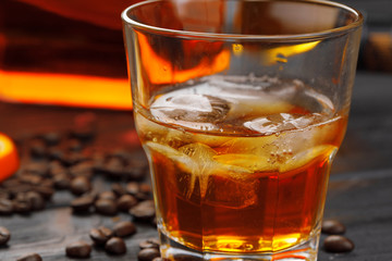 Whiskey or liqueur, coffee beans and orange cut on wooden background. Seasonal holidays concept.
