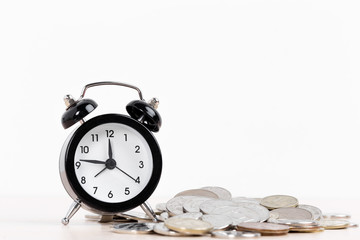 Alarm clock and coins on white background