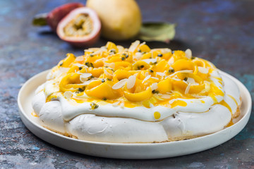 Meringue cake Pavlova with fresh mango and passion fruit and whipped cream on slate, stone or...