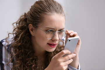 Woman with bad sight trying to read message on screen of mobile phone