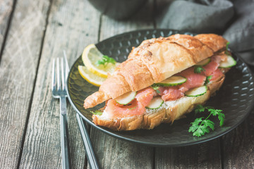 smoked salmon sandwich with cream cheese fresh and cucumbers on black plate