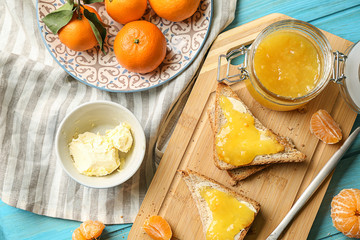 Bread with butter and tasty tangerine jam on wooden table