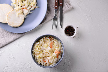 Bowl with tasty fermented cabbage on white table