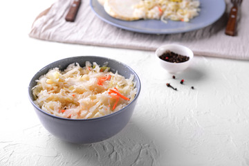 Bowl with tasty fermented cabbage on white table