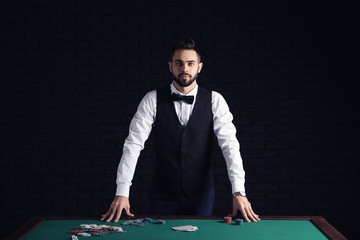 Male banker with cards at table in casino