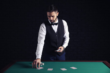 Male banker with cards at table in casino