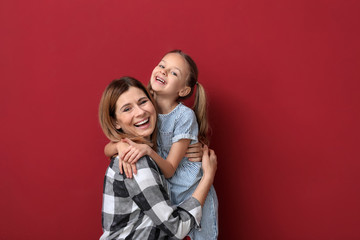 Portrait of happy mother with daughter on color background