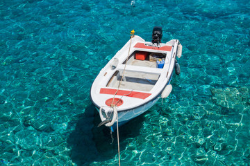 Fototapeta na wymiar White boat at crystal clear blue water of Marmara beach, near Aradena gorge, island of Crete, Greece