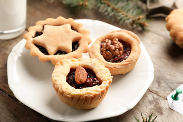 Plate with tasty mince pies on wooden table