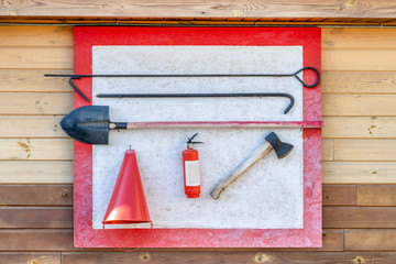 Wall-mounted fire shield with fire-fighting tools. Shovel, hook , axe, cone bucket, fire extinguisher and other equipment hanged on fire point