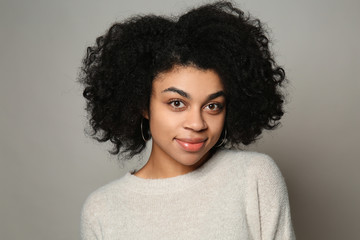 Portrait of young African-American woman on grey background