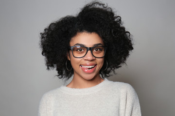 Obraz premium Portrait of young African-American woman wearing glasses on grey background