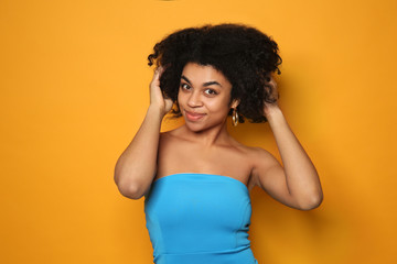 Portrait of young African-American woman on color background