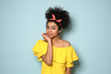 Portrait of young African-American woman on color background