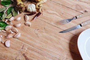 White plate with a fork and spoon On the wood background. Tableware.with herbs and greens. Ingredients for cooking, - Copy Space.