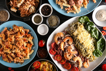 Plates with different pasta on table, top view