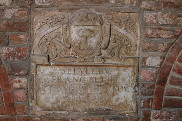 Old italian medieval brick wall with low relief . Stone and brick texture or background.Orange and brown grunge background. Tuscan architecture. Ancient wall.