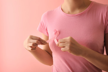Woman with pink ribbon on color background. Breast cancer awareness concept