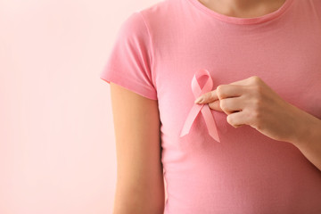Woman with pink ribbon on color background. Breast cancer awareness concept - Powered by Adobe