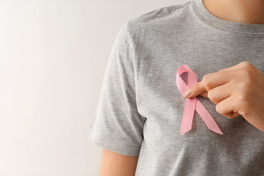 Woman with pink ribbon on light background. Breast cancer awareness concept