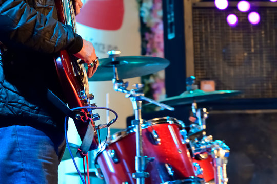 Close-up of guitarist playing guitar in live concert on stage. 