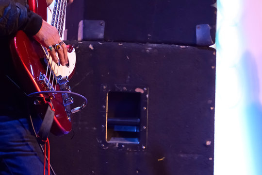 Close-up of guitarist playing guitar in live concert on stage. 