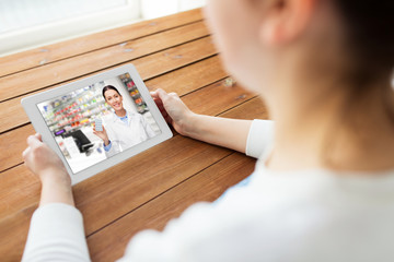 medicine, technology and healthcare concept - close up of woman having video chat with pharmacist on tablet pc computer at home