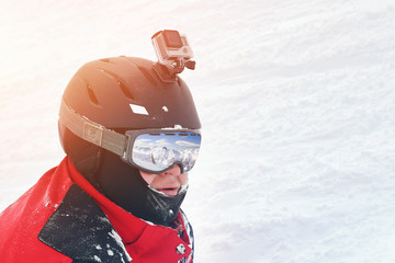 Snowboarder or skier portrait in sport goggles and protection helmet with mounted action camera and...