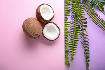 Fototapeta na wymiar Coconuts and tropical leaves on color background