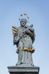 Obraz premium Statue of Saint John of Nepomuk in Olesno, Poland with gold elements: palm of martyrdom, halo of five stars, robes and crucifix cross with Jesus. St John is the Patron Saint of Bohemia & Confession.