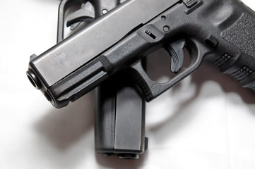 Two black semi automatic pistols, a 9mm and a 40 caliber with one on top of the other on a white...