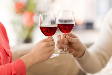 celebration, drinks and alcohol concept - hands of couple clinking red wine glasses
