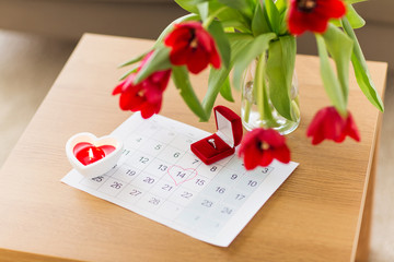 valentines day, jewelry and holidays concept - diamond ring in red velvet gift box and calendar sheet with 14th february date marked by heart shape