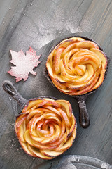 Homemade puff pastry with rose shaped apple slices baked in iron skillet