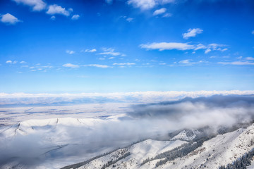 Scenic alpine landscape with fog under mountains, forest and blue sky. National park of Kyrgyzstan....
