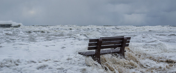 STORM AT SEA - A bench flooded by storm waves on a sea beach in Kolobrzeg
