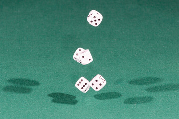 Five white dices falling on a green table